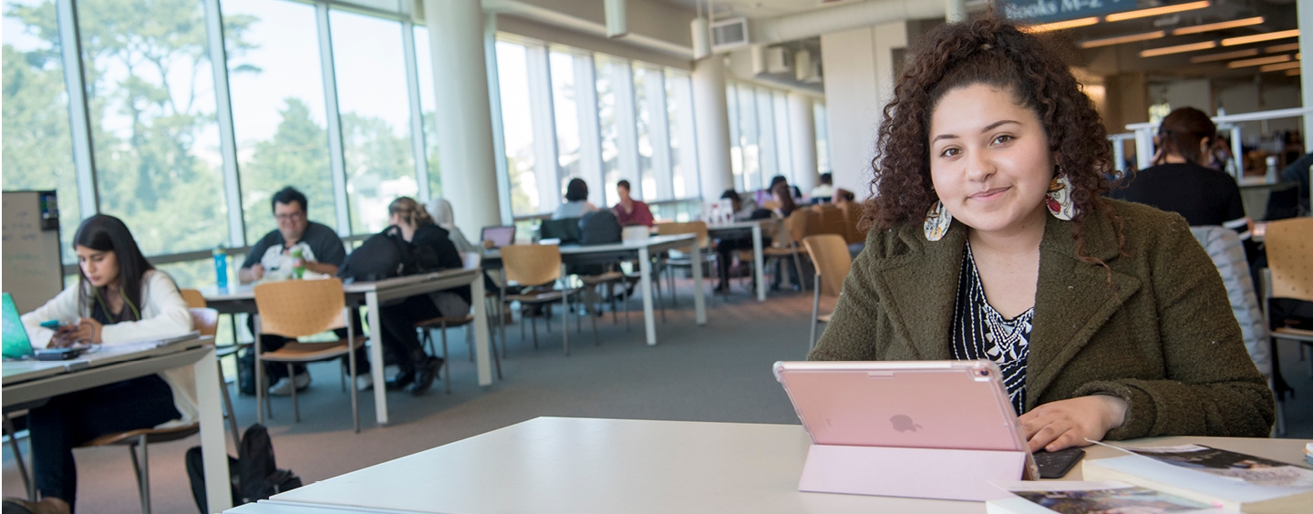 young Latino women in library using ipad computer