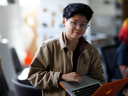 women standing while holding a orange laptop